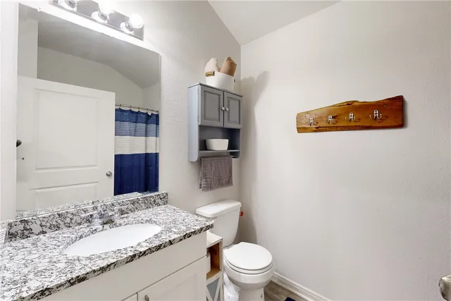 a bathroom with a granite countertop sink a toilet and shower