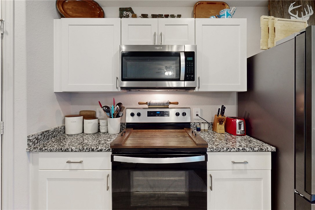 137 Windmill Road Somerville, TX 77879 - Photo 7 of 22 a kitchen with granite countertop a stove and a microwave