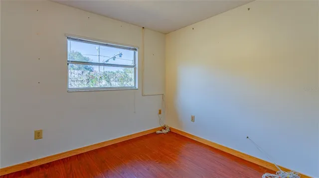 a view of an empty room with wooden floor and a window