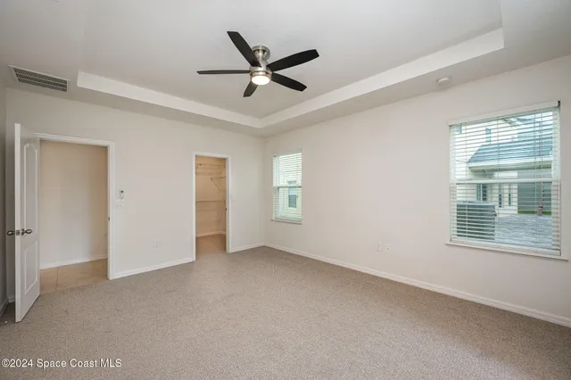 a view of a livingroom with a ceiling fan & windows