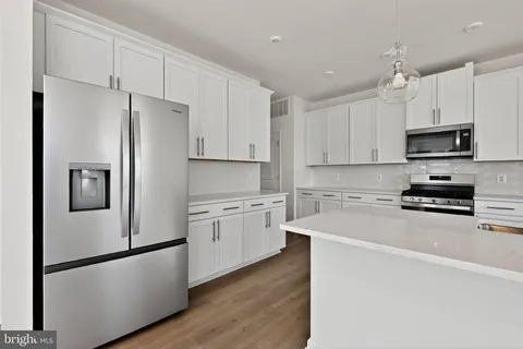 a kitchen with stainless steel appliances a refrigerator sink and white cabinets