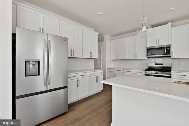 a kitchen with stainless steel appliances a refrigerator sink and white cabinets