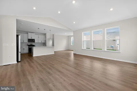 a view of empty room with kitchen and window