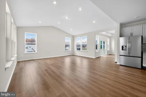 a view of a kitchen with refrigerator and wooden floor