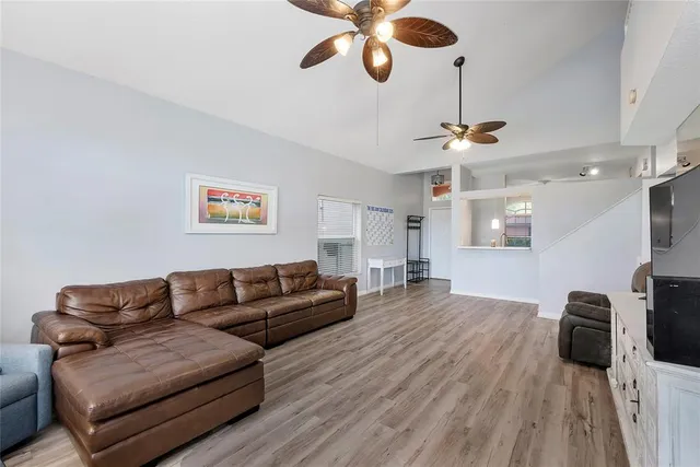 a living room with furniture a ceiling fan and a wooden floor