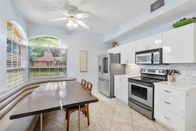 a kitchen with stainless steel appliances granite countertop a stove a sink dishwasher a refrigerator with a dining table and chairs