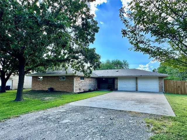 a view of a house with a yard and a large tree