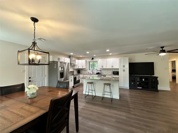 a living room with stainless steel appliances furniture and a flat screen tv