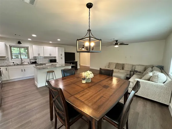 a view of a dining room and livingroom with furniture wooden floor a chandelier