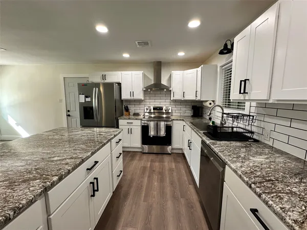 a kitchen with a refrigerator a stove top oven a sink and cabinets