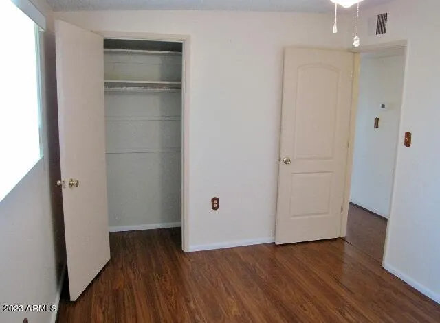 an empty room with wooden floor & closet and windows