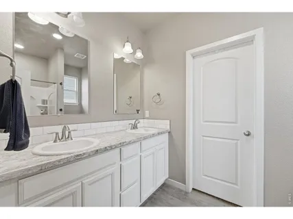 a bathroom with a granite countertop sink a large mirror and a shower