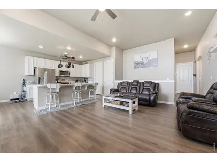 a kitchen with stainless steel appliances kitchen island granite countertop a sink dishwasher a microwave oven a stove with white cabinets and wooden floor