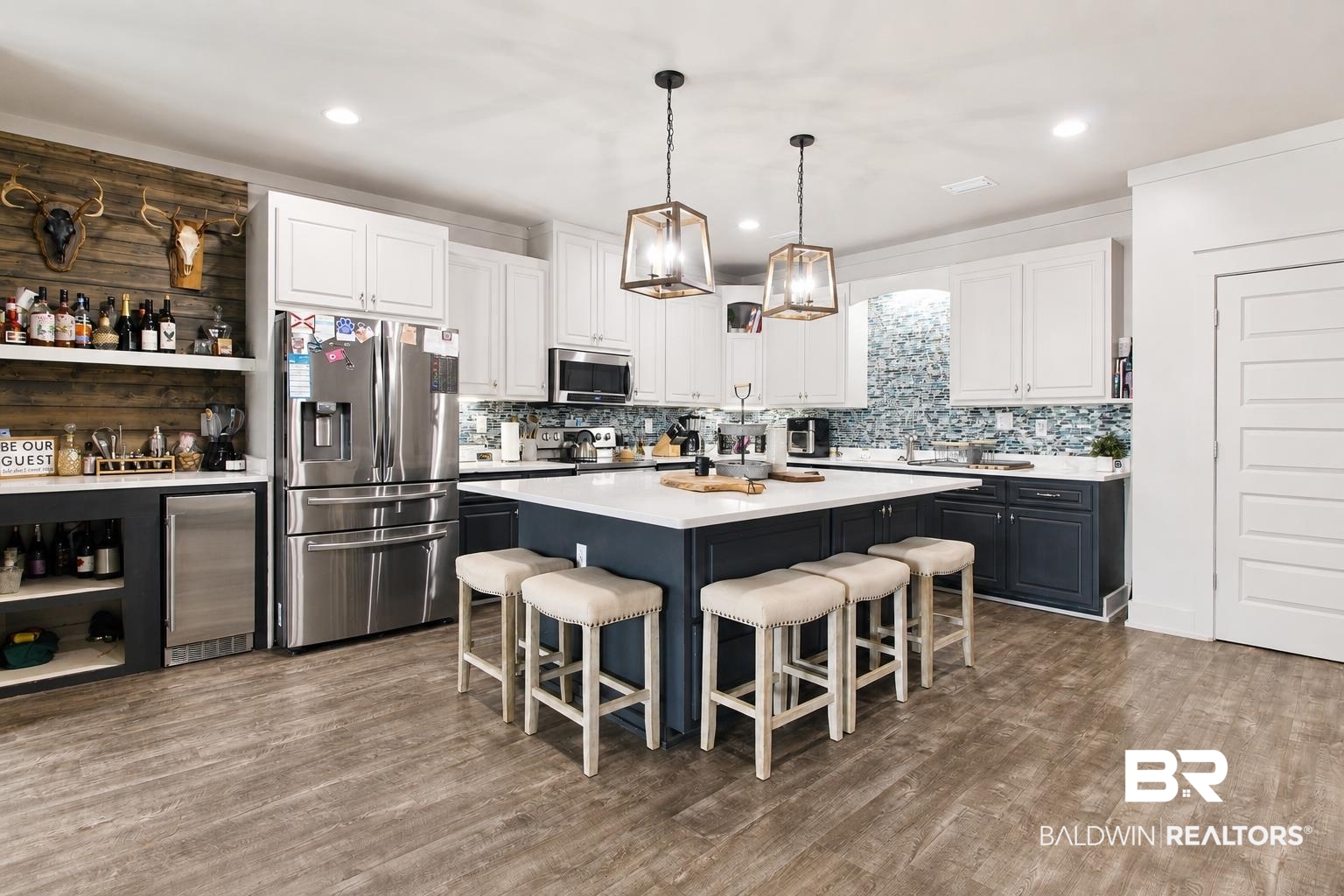 9825 Wolf Creek Ridge Elberta, AL 36530 - Photo 32 of 76 Spacious kitchen featuring a large central island with seating, wood-finish flooring, two-tone cabinetry, stainless steel appliances, and a mosaic tile backsplash