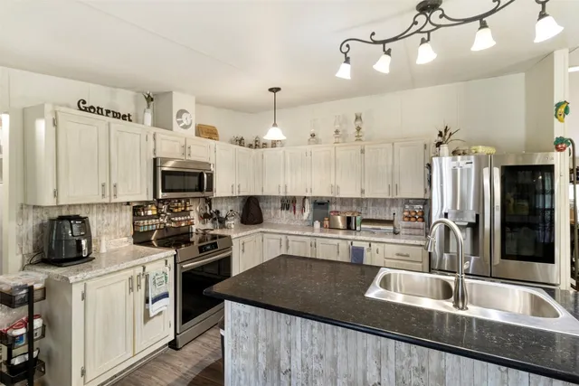 a kitchen with stainless steel appliances granite countertop a sink a stove and refrigerator
