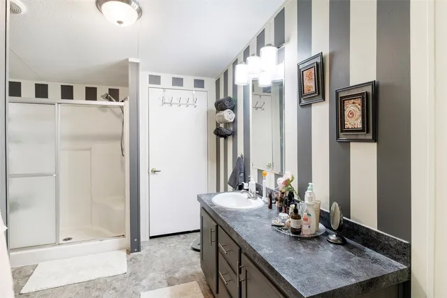 a bathroom with a granite countertop sink a mirror and shower