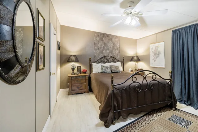 a bedroom with a bed a mirror and a lamp on the dresser