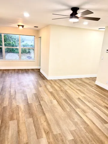 a view of an empty room with wooden floor and a window