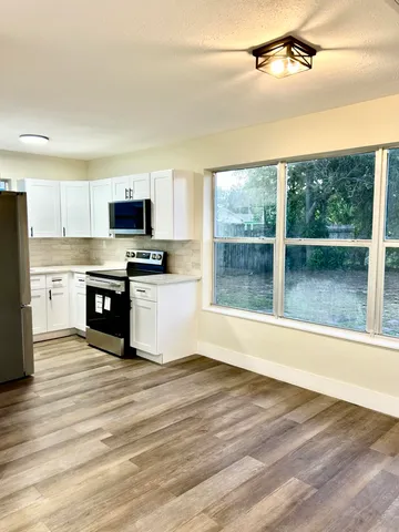 a view of kitchen with granite countertop a stove top oven a sink with a dining table and chair