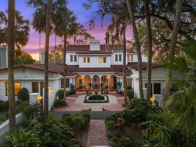 a front view of a house with garden and trees
