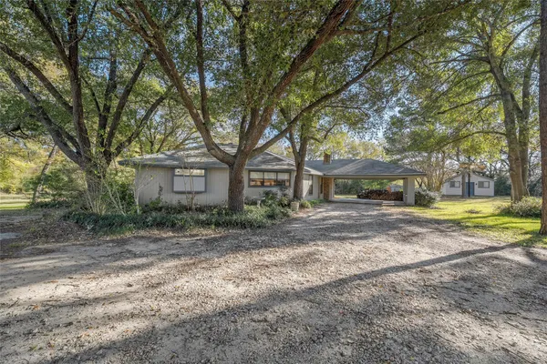 a view of a house with a yard and large trees