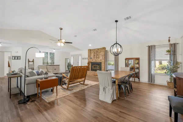 a living room with couches chairs and kitchen view with wooden floor