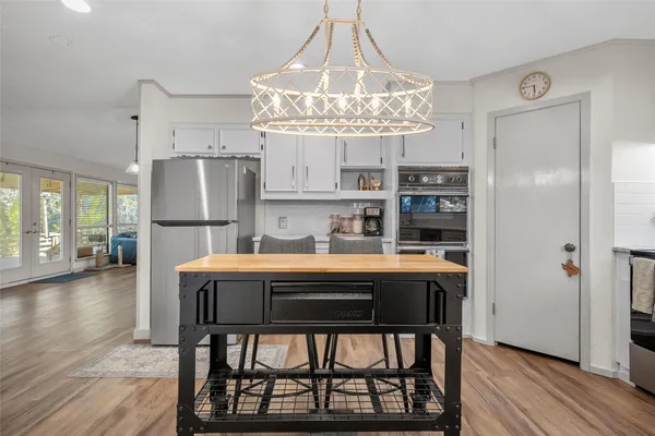 a kitchen with stainless steel appliances a dining table chairs refrigerator and cabinets