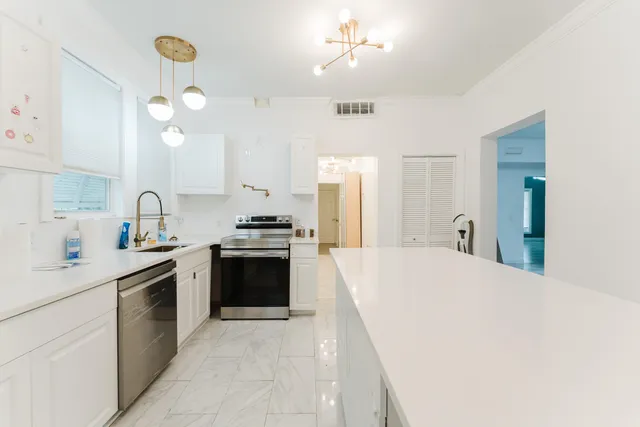 a kitchen with a sink a stove cabinets and wooden floor