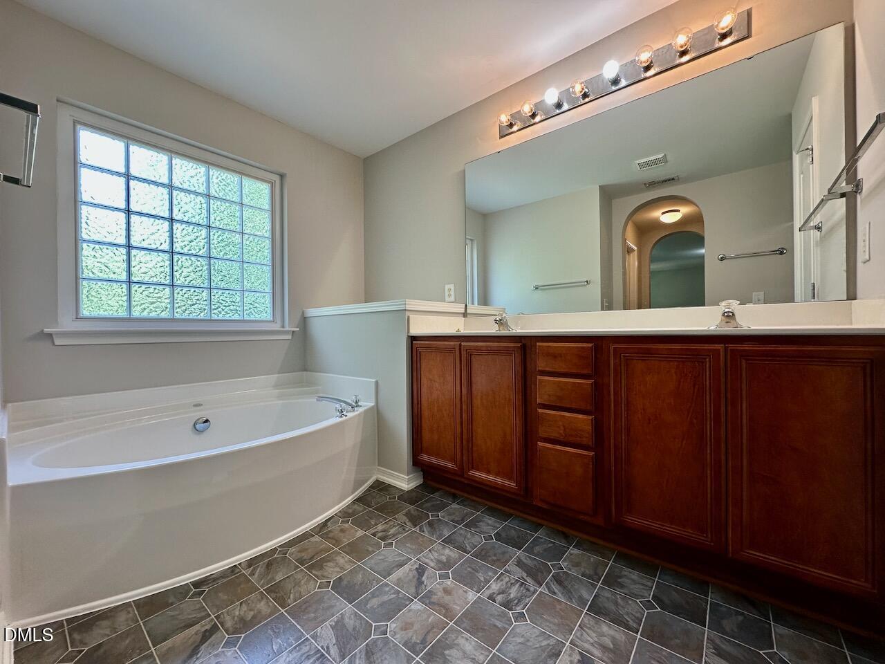 8208 Stone Cellar Drive Raleigh, NC 27613 - Photo 21 of 34 a spacious bathroom with a double vanity sink and a bathtub