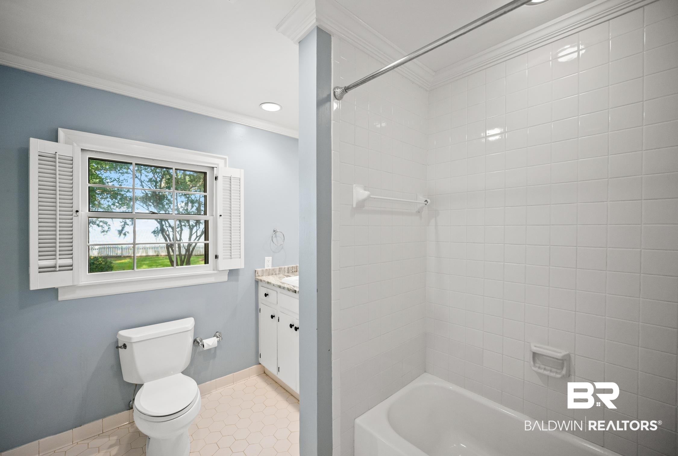 5490 Battles Road Fairhope, AL 36532 - Photo 25 of 47 Bathroom featuring a window with white louvered shutters, a white toilet, a vanity with a light-toned countertop and white cabinetry, a white bathtub, and white square tile shower surround