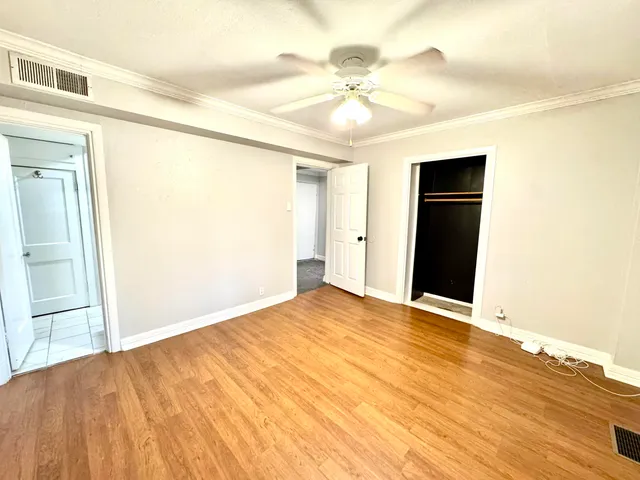 a view of an empty room with wooden floor and a ceiling fan