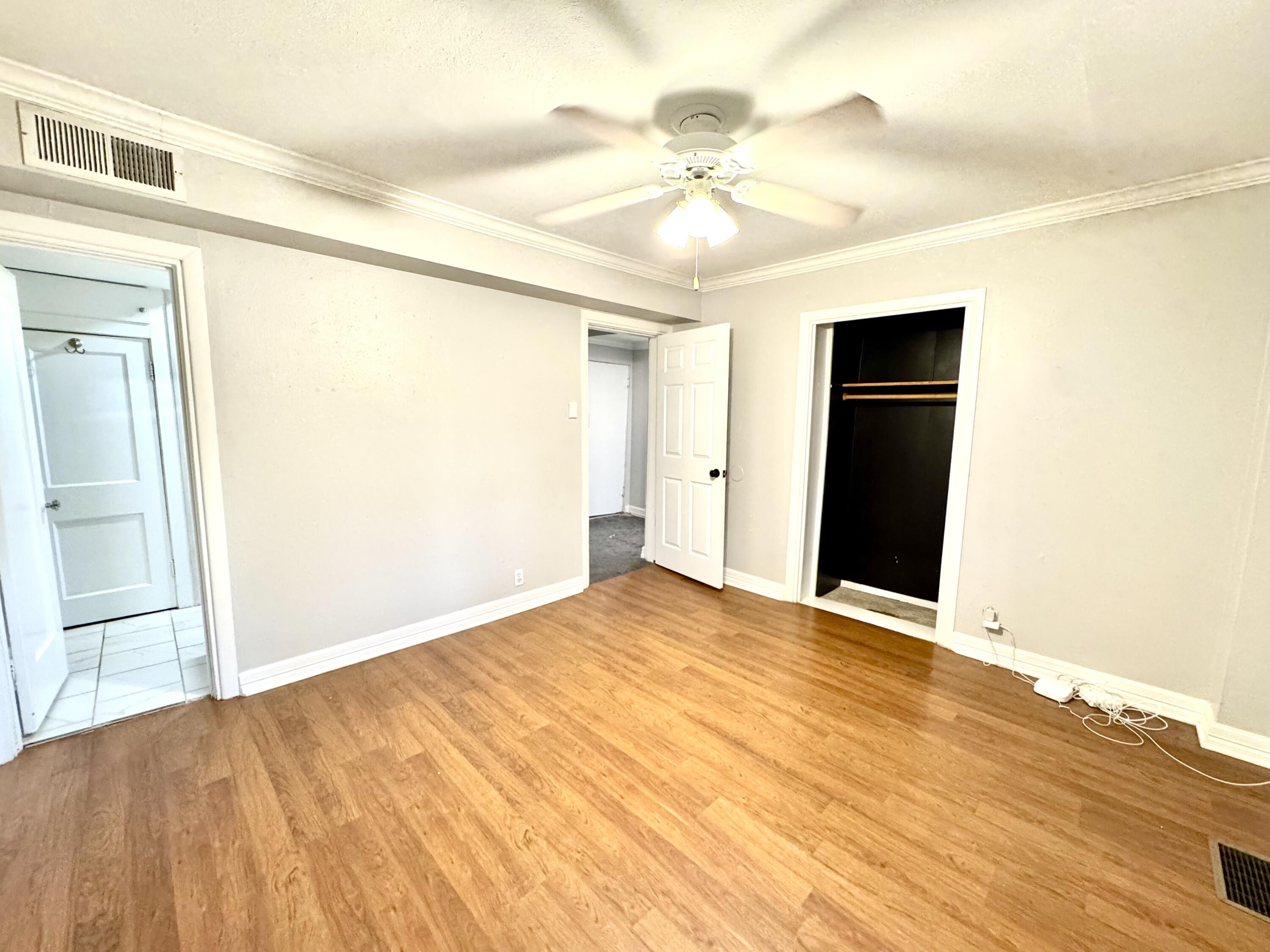 2702 23rd Street, Unit FRONT Lubbock, TX 79410 - Photo 12 of 22 a view of an empty room with wooden floor and a ceiling fan