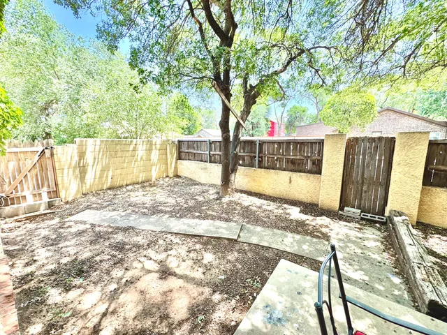 a view of a backyard with large trees and wooden fence