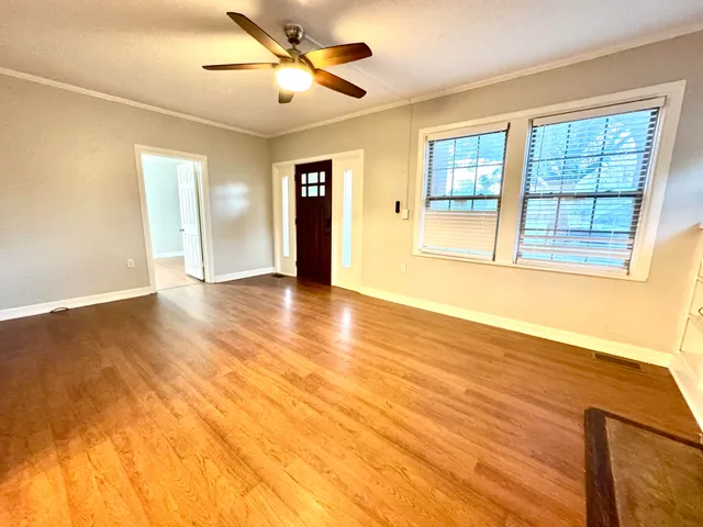 a view of an empty room with wooden floor and a window