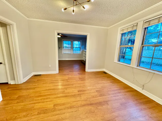 a view of an empty room with window and wooden floor