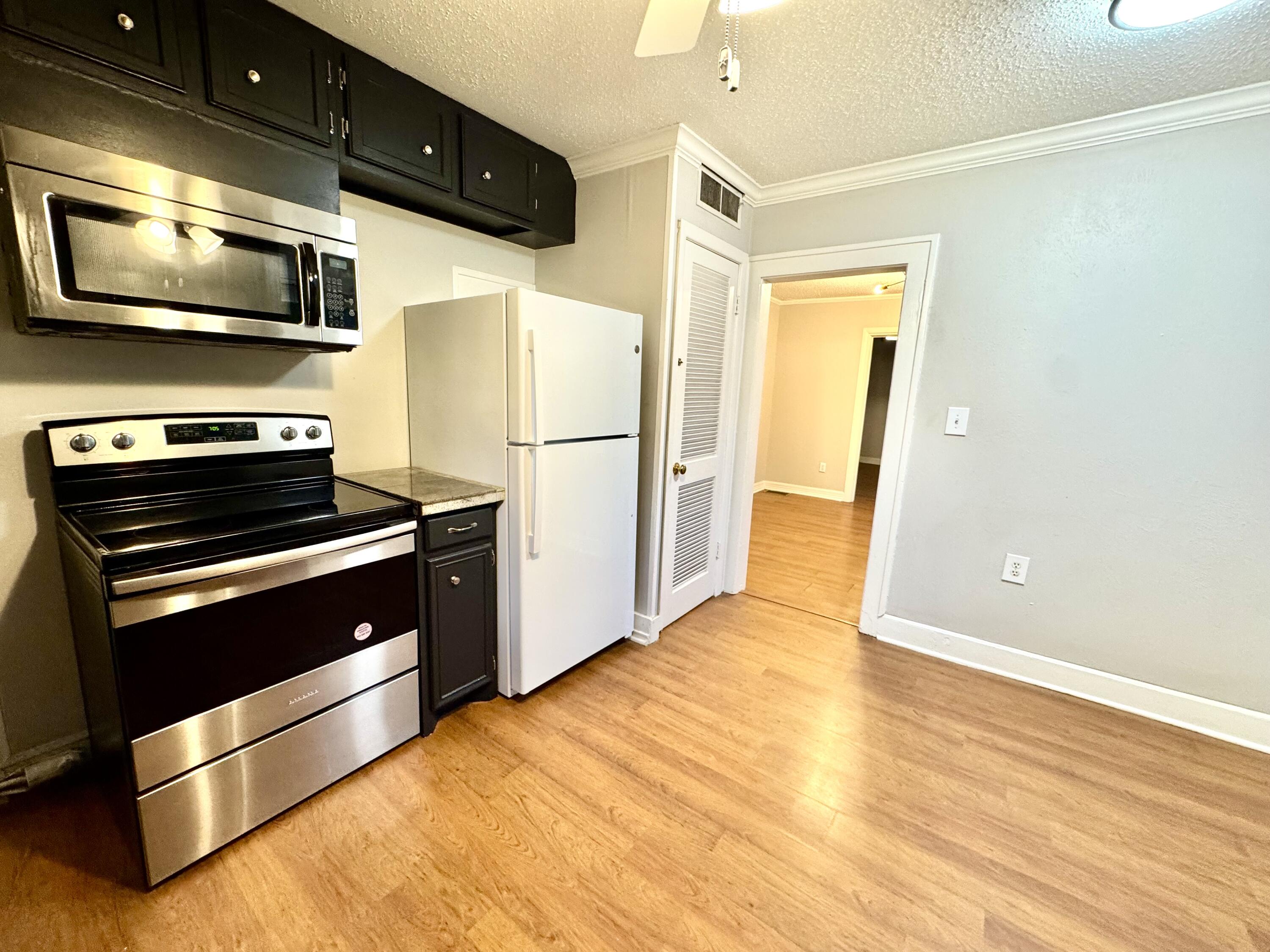 2702 23rd Street, Unit FRONT Lubbock, TX 79410 - Photo 9 of 22 a kitchen with stainless steel appliances a microwave a stove and a refrigerator