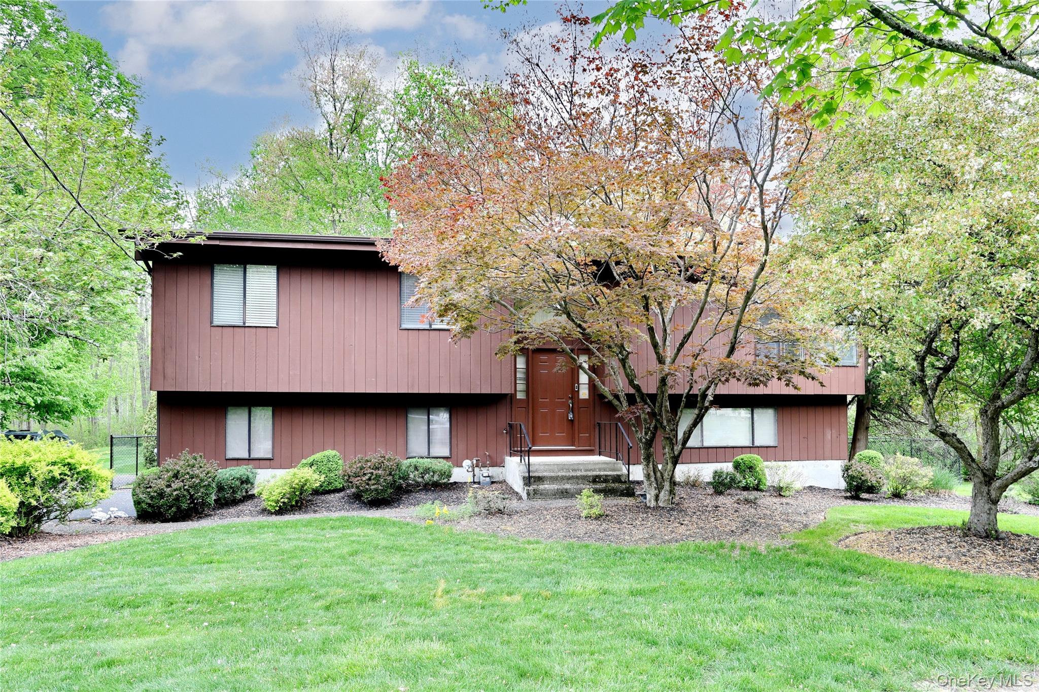 a brick house with a yard plants and a large tree