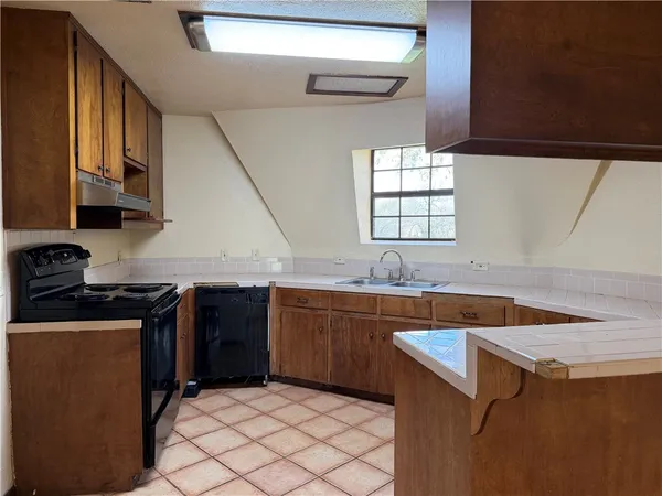 a kitchen with granite countertop a sink dishwasher stove and cabinets