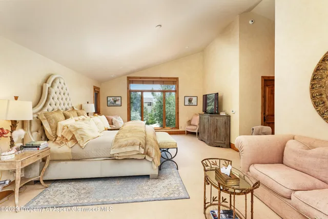 a spacious bedroom with a bed a couch and large windows