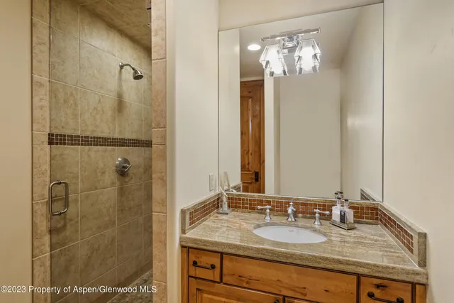 a bathroom with a granite countertop shower a mirror and a sink