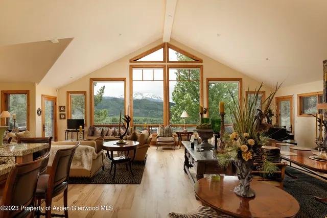 a living room with couches a dining table and chairs with floor to ceiling window