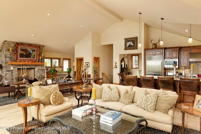 a living room with furniture kitchen view and a chandelier