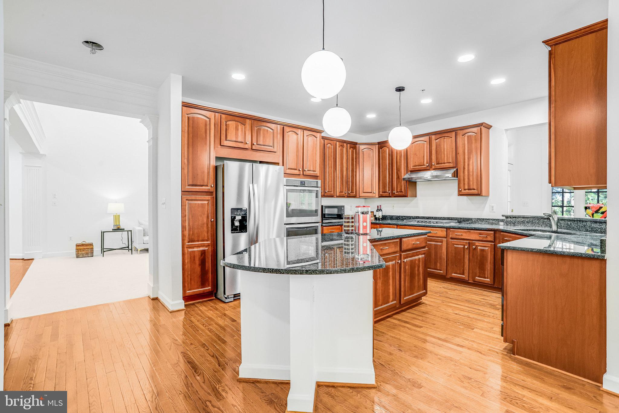 13107 English Turn Drive Silver Spring, MD 20904 - Photo 27 of 73 a kitchen with stainless steel appliances granite countertop a refrigerator a sink dishwasher a stove and a dining table with wooden floor
