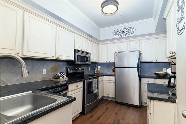 a kitchen with stainless steel appliances granite countertop a refrigerator a stove and a sink