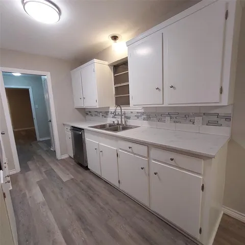 a kitchen with a sink cabinets and wooden floor