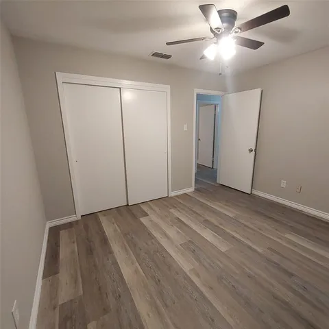 an empty room with wooden floor fan and windows