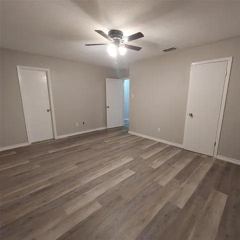 an empty room with wooden floor and fan