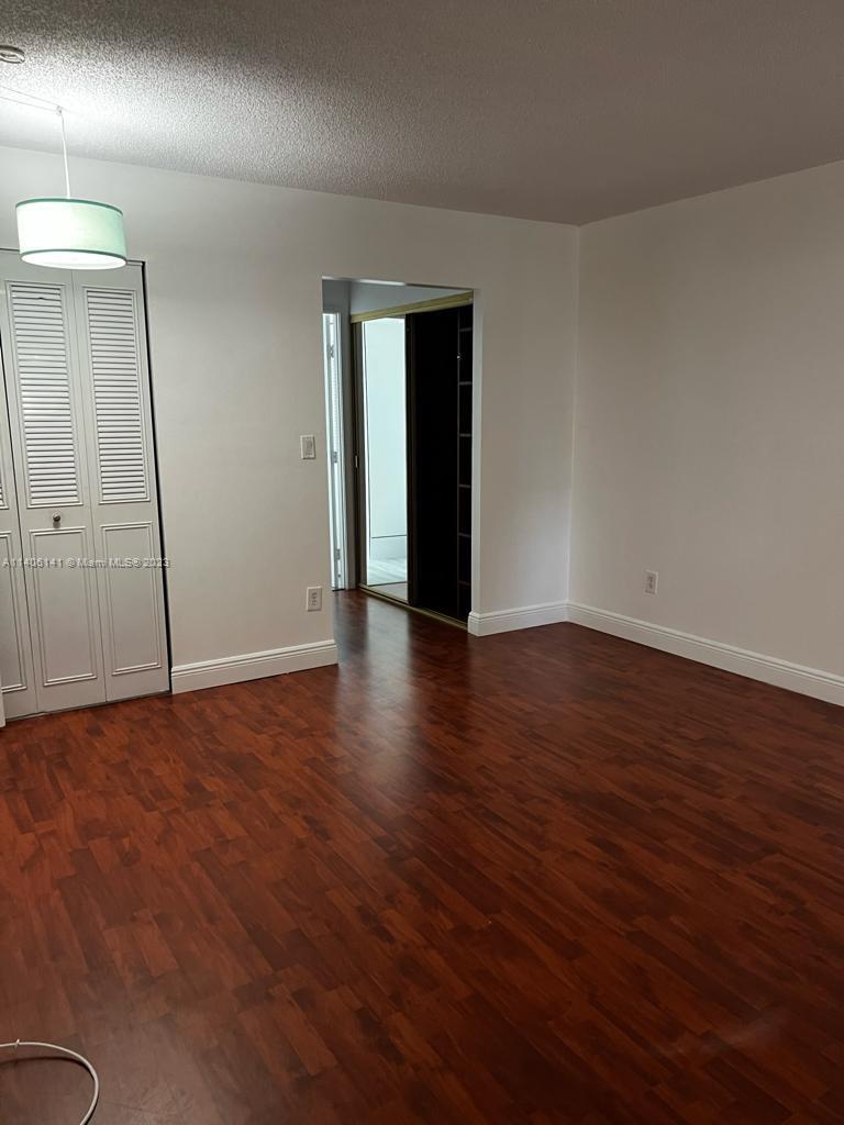 6800 Cypress Road, Unit 211 Plantation, FL 33317 - Photo 7 of 19 an empty room with wooden floor and mirror