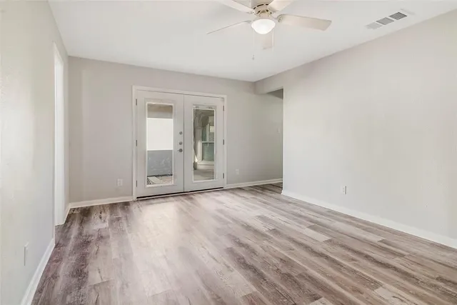 an empty room with wooden floor and fan