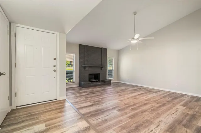 a view of a livingroom with a fireplace a ceiling fan and wooden floor